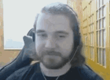 a man with a beard wearing headphones is sitting in a chair .