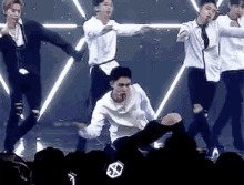 a group of young men are dancing on a stage in front of a crowd of people .