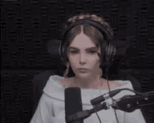 a woman wearing headphones is sitting in front of a microphone in a room .