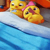 a couple of stuffed ducks are laying on a bed looking at their phones