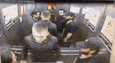 a group of men are standing in an elevator and talking .