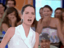 a woman in a white top is standing in front of a crowd