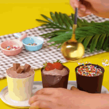 a person is adding sprinkles to a cup of dessert with a strawberry on top