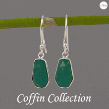 a coffin shaped ring with a green stone sits on a wooden table