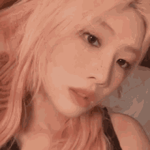 a close up of a woman 's face with pink hair .