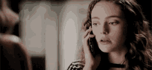 a woman is talking on a cell phone and looking at the camera .