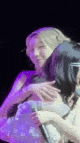 two women hugging each other on a stage with a microphone