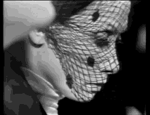a woman is wearing a veil over her face in a black and white photo .