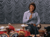 a man is singing into a microphone while playing drums