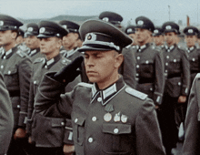 a man in a military uniform salutes in front of a group of men