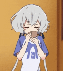 a girl with white hair and a blue shirt with the number 4 on it is eating something .