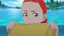 a girl with red hair is holding a yellow cloth in front of a lake