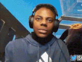 a young man wearing headphones and a blue hoodie with the word adidas on it