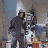 a man in a hoodie is standing in front of a desk