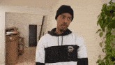 a man wearing a black beanie and a white supreme sweatshirt