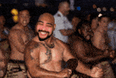 a shirtless man with a tattoo on his arm is smiling in front of a crowd