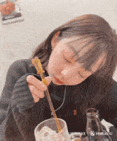 a girl is drinking from a glass with a straw and a sign that says 450 yen