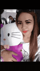 a woman holding a hello kitty stuffed animal in her lap