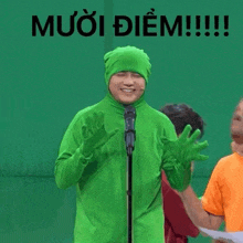 a man in a green suit stands in front of a microphone with the words muoi diem written on the bottom