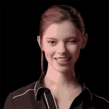 a woman wearing a black shirt with white stripes on the collar is smiling