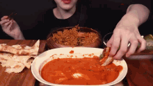 a person is dipping a piece of pizza into a bowl of food