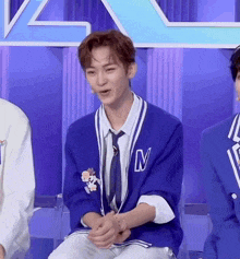 a man in a blue jacket and tie with the letter n on it