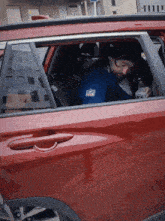 a man sitting in a red car wearing a blue shirt that says nfl