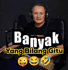 a man wearing headphones is sitting in front of a microphone with the words banyak yang bilang jitu written above him
