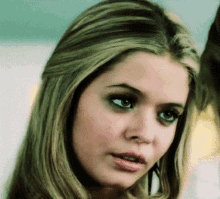 a close up of a woman 's face with blonde hair and green eyes