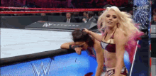 a woman in a bikini is wrestling another woman in a wrestling ring
