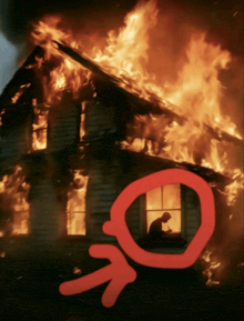 a man sits in a window of a burning house with a red arrow pointing to it