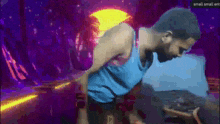 a man in a blue tank top is standing in front of a purple background with the words small small ent on the bottom