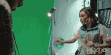 a woman stands in front of a green screen with bravas written on the bottom