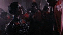 a woman in a black dress is standing in a crowd of people in a dark room .