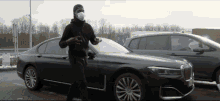 a man wearing a mask is standing in front of a car