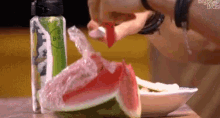 a person is cutting a slice of watermelon with a knife .