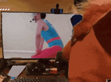a computer screen shows a man in a blue tank top and pink shorts