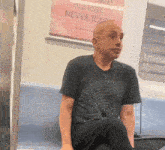 a man is sitting on a train with a poster that says almost never told