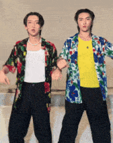 two young men wearing hawaiian shirts are dancing