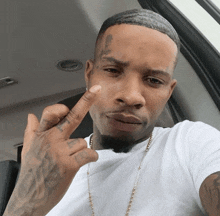 a man with a tattoo on his forehead is giving a middle finger