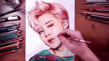 a drawing of a girl with pink hair is being painted on a table with colored pencils