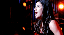 a woman is singing into a microphone in a dark room