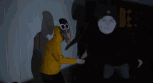 a man wearing a yellow hoodie and goggles is standing next to another man