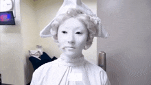 a woman with white paint on her face is wearing a hat