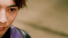 a close up of a person 's face with a purple shirt on