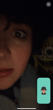 a phone screen shows a man with glasses and a hat