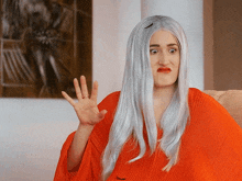 a woman with long white hair is wearing a red shirt and making a funny face