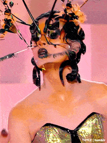 a woman with insects painted on her face is wearing a gold dress