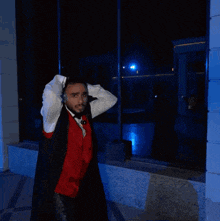 a man in a red vest and bow tie holds his head in his hands