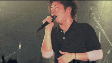 a man is singing into a microphone on a stage